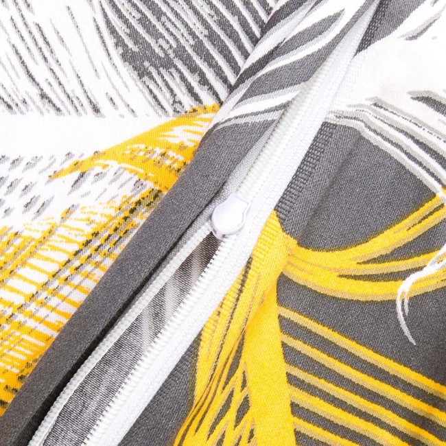 Zbliżenie na zamek błyskawiczny pościeli satynowej w rozmiarze 180x200 cm z białymi i złotymi piórami na szarym tle. Widoczna faktura materiału oraz żółte detale na tle szaro-białym. Zamek w kolorze białym, umieszczony na krawędzi poduszki.