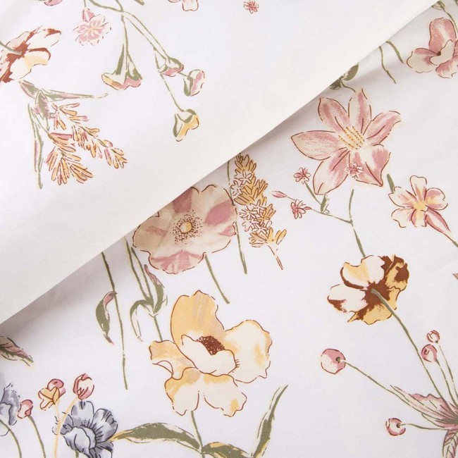 Pościel satyna bawełniana 140x200 w kolorze jasnego kremu, z delikatnymi kwiatowymi wzorami w odcieniach różu, żółci i zieleni. Widok z góry, rozłożona na białym tle, ukazująca subtelną teksturę materiału i detale kwiatów.