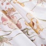 Pościel satyna bawełniana 140x200 Floralis w delikatne kremowe kwiaty na białym tle, leżąca w złożeniu. Wzór obejmuje pastelowe odcienie różu i żółci, z widocznymi detalami kwiatów. Tło jest jasne i jednolite, co podkreśla wzory.