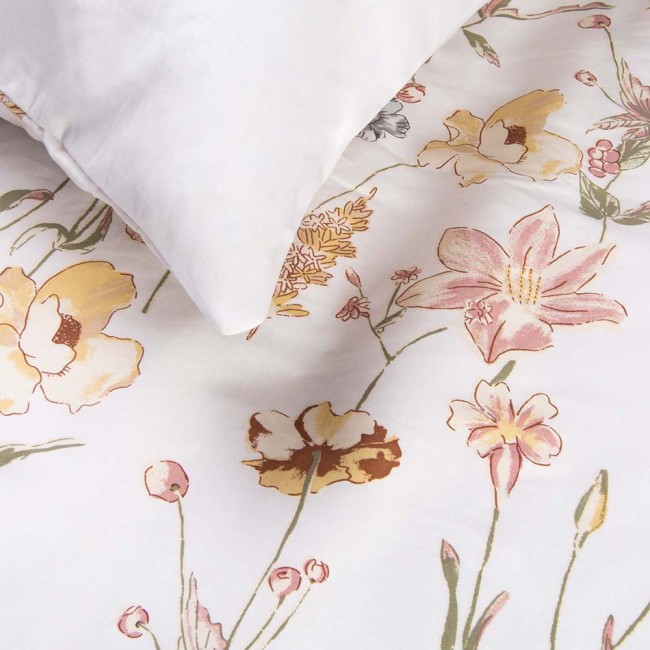 Pościel satyna bawełniana 140x200 w delikatny kremowy wzór kwiatowy na białym tle. Poduszka leżąca na pościeli. Widoczne detale w postaci kwiatów w odcieniach różu i żółci, z teksturą gładkiej satyny.
