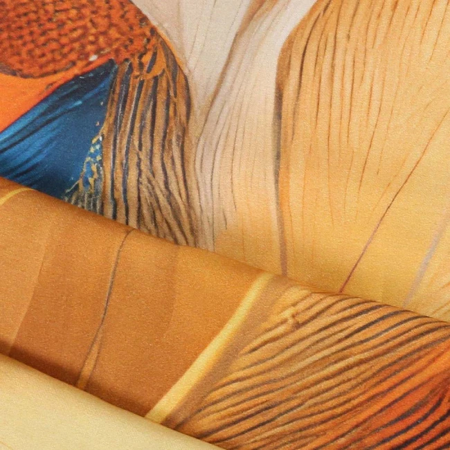 Poszewka satynowa 40x40 Aurelia w kolorze złotym i niebieskim z liściastym wzorem. Produkt leży na płasko, ukazując jego gładką, błyszczącą teksturę oraz szczegóły nadruku. Tło w neutralnym odcieniu podkreśla kolorystykę poszewki.