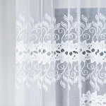Firana gotowa BASTIA żakardowa, biała, o wymiarach 300x160 cm, zawiera delikatny wzór z motywem liści i kwiatów na dolnej części. Produkt jest zawieszony w pionie, z widocznym, lekko prześwitującym materiałem. Tło jest jasne i jednolite.