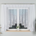 Firana gotowa BERENIKA, żakardowa w kolorze białym, o wymiarach 400x160 cm. Wykończona koronkowym haftem u dołu, zwisająca z karnisza, w aranżacji okna. Tło jasne, z widoczną doniczką z kwiatami na parapecie.