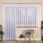 Firana gotowa MODESTA, żakardowa, biała, o wymiarach 200x250 cm, zawieszona na karniszu, z delikatnym wzorem na dolnej krawędzi. Widoczna w kontekście nowoczesnego wnętrza z szaro-złotym fotelem i stolikiem. Tło w kolorze jasnobeżowym.
