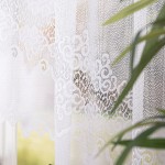 Firana gotowa MODESTA żakardowa, 400x160 cm, w kolorze białym, z delikatnym wzorem koronki u dołu. Widok frontalny, produkt wiszący na karniszu, otaczany roślinnością. Tło w odcieniach zieleni, dodające naturalnego akcentu do aranżacji.