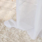 Firana gotowa NALA na przelotkach, biały materiał o gładkiej fakturze, prezentująca się w opadającej pozycji na jasnozłotej podłodze. Widoczna część przelotki, podkreślająca sposób zawieszenia. Tło intensywnie neutralne.