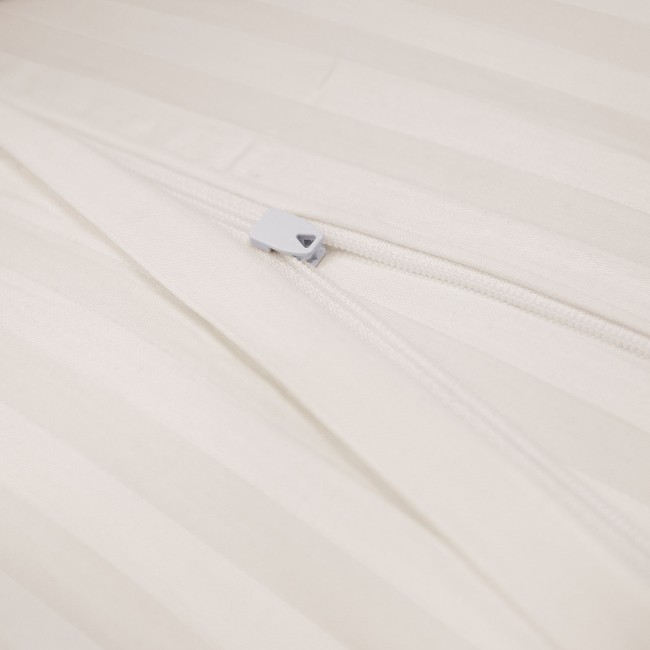 Pościel satyna bawełniana w kolorze kremowym, z widocznym zamkiem błyskawicznym. Ujęcie w zbliżeniu, skupiające się na detalu mocańca, na tle jasnego materiału o delikatnych, poziomych prążkach. Produkt leży płasko.