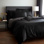 Pościel bambusowa satyna bawełniana 160x200 w kolorze czarnym z delikatnym wzorem pasków. Ułożona na łóżku z szarym poszyciem, z kilkoma poduszkami w różnych rozmiarach. Otoczenie nowoczesne, z lampą i kwiatami na stoliku nocnym, na tle białej ściany.