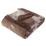 Bawełniany koc 150x200 cm w brązowym kolorze, dwustronny, z frędzlami. Ułożony w poziomie z lekko wysuniętą jedną stroną, ukazującą jasny wzór liści. Miękka faktura tkaniny, idealny do wnętrz. Posiada estetyczne wykończenie.