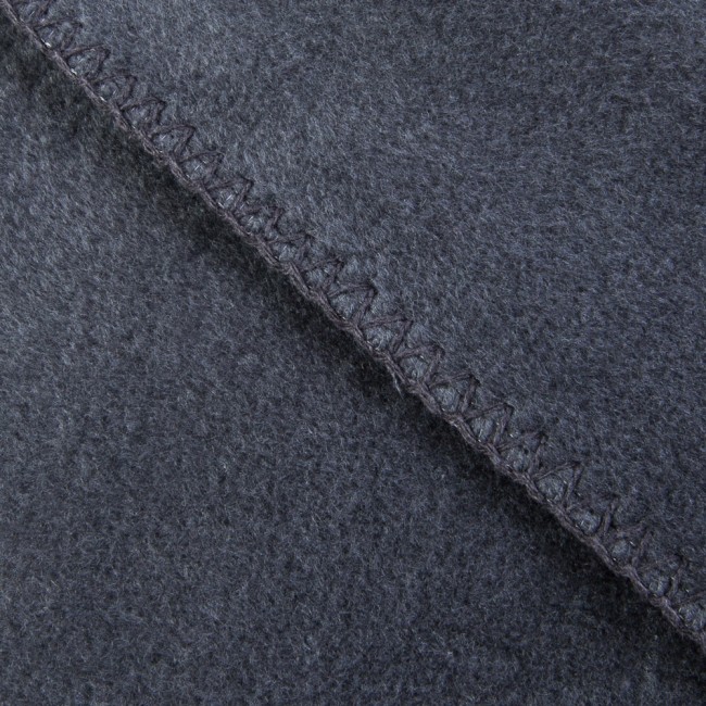 Koc bawełniany o wymiarach 150x200 cm w ciemnoszarym kolorze, z frędzlami, pokazany w zbliżeniu. Widoczna faktura materiału oraz staranne wykończenie brzegów, które są obszyte wzdłuż krawędzi.