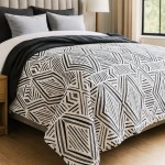 Narzuta drukowana Tarik 170x210 w biało-czarnym wzorze geometrycznym, rozłożona na łóżku. Widoczne poduszki w odcieniach szarości. Tło jasne, drewniana podłoga tworzy neutralny kontekst. Zbliżenie na detale wzoru i fakturę materiału.