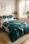 Pościel satyna bawełniana 140x200 w odcieniach szarości z zielonymi liśćmi, ukazana na łóżku w leżakowanej pozycji. Poduszki z tym samym wzorem, tło jasne, dekoracyjne rośliny w doniczkach obok. Wzór liści podkreślony delikatnym złotym konturem.