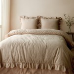 Pościel bawełniana 220x200 cm w odcieniu beżowym, z falbanką na brzegach. Zestaw obejmuje narzutę oraz dwie poduszki z falbaniastymi krawędziami. Ułożona na łóżku w jasnym otoczeniu, z naturalnym światłem wpadającym przez okno.