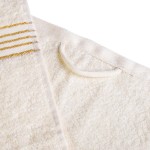 Komplet ręczników z bawełny w kolorze ecru, z bordiurą w złote paski, o gramaturze 500 g/m2. Ręczniki mają pętelkę do zawieszenia, prezentowane w eco pudełku. Widok z boku na teksturę oraz detale wzoru.