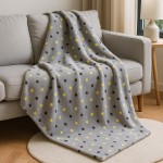 Puszysty koc dekoracyjny 150x200 w jasnym szarym kolorze z wzorem w żółte i brązowe kropki, leżący na szarej sofie. Koc wykonany z miękkiego materiału, idealny do użytku w salonie lub sypialni.