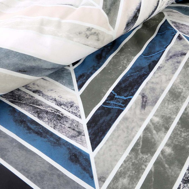 Pościel bawełniana 220x200 Bluewave w geometryczny wzór, z dominującymi odcieniami niebieskiego, szarości i bieli. Materiał gładki, z wyraźnym, złożonym wzorem w kształcie trójkątów, ułożony w sposób odsłaniający detale.
