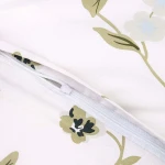 Pościel bawełniana 140x200 w kolorze białym z wzorem kolorowych kwiatów. Widoczny zamek błyskawiczny na poszewce. Materiał gładki, z delikatnym nadrukiem roślinnym w odcieniach zieleni i niebieskiego.