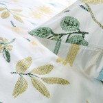 Biała pościel bawełniana 160x200 Sunny Meadow z letnim motywem łąki, z zielonymi i żółtymi wzorami liści oraz kwiatów. Poduszka widoczna w zbliżeniu, materiał gładki, o delikatnej fakturze. Pościel ułożona na płasko.