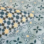 Pościel bawełniana 200x220 cm w niebieskim kolorze z mozaikowym motywem. Wzór składa się z geometrycznych kształtów w odcieniach granatu, żółci i bieli. Widoczna poszewka na poduszkę z detalami wzoru, leżąca na płaskiej powierzchni.