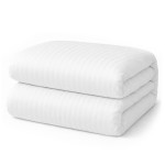 Pościel hotelowa bawełniana 160x200 cm w białe pasy 1 cm, z zakładką 30 cm. Ułożona w stos, z widoczną gładką teksturą materiału.