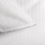 Pościel bawełniana 140x200 w białe pasy 1 cm, z zamkiem i 30 cm zakładką. Ujęcie z góry, z bliska na detal poszewki poduszki, prezentujące teksturę tkaniny i precyzyjne wykończenie. Tło jednolite, ukazuje czystość i prostotę produktu.