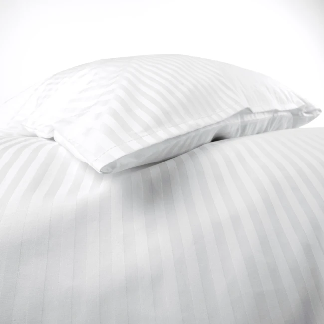 Poszewka hotelowa na poduszkę 70x80 cm, biała w paseczki o szerokości 1 cm, leżąca w układzie złożonym. Materiał gładki, z delikatnym połyskiem, na jednolitym tle. Widoczne szwy i krawędzie, brak napisów oraz logo.