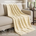 Puszysty koc dekoracyjny 200x220 cm w kolorze żółtym z limonkowymi kropkami, leżący na beżowej kanapie. Wykonany z miękkiego materiału, idealny do użytku w salonie lub sypialni, zapewniając ciepło i komfort.