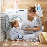 Puszysty koc dekoracyjny 150x200 w jasnym niebieskim kolorze laguna z kolorowymi kropkami. Produkt w rękach kobiety, przy pralce, w otoczeniu drewnianych ścian. Idealny do codziennego użytku, łatwy w praniu. Koc miękki i ciepły.