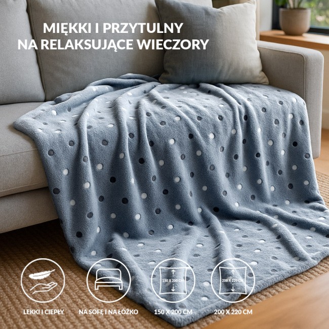 Puszysty koc dekoracyjny 150x200 cm w ciemnym niebieskim kolorze z wzorem w kropki. Miękki i ciepły, leżący na jasnej sofie, idealny do użytku na łóżku lub w salonie. Tekstura pluszowa, długość 150 cm, szerokość 200 cm.