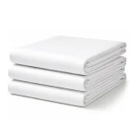 Prześcieradło bawełniane hotelowe, białe 140x200 cm, leżące na gładkiej powierzchni. Widoczne złożone elementy, w tym górna część wywinięta.