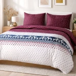 Pościel flanelowa 220x200 w bordowym kolorze z białymi i czerwonymi kwadratami, z wzorem renifera na beżowym tle. Poduszki w tym samym kolorze, leżąca na łóżku. Widok z przodu, w aranżacji sypialni. Stolik nocny z lampką w tle.