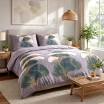 Pościel flanelowa 180x200 cm w szarym kolorze, z motywem liści miłorzębu w jasnych i ciemnych odcieniach zieleni oraz beżu, rozłożona na łóżku. Poszewki na poduszki z tym samym wzorem, w tle lampka nocna na drewnianym stoliku.