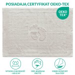 Dywanik łazienkowy o wymiarach 50x70 cm w kolorze popielatym. Frontalne ujęcie ukazuje fakturę materiału z wytłoczonym wzorem stóp, ozdobiony wypukłymi punktami. Otoczony miękką, gładką krawędzią, leży na jednolitym tle.