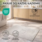 Dywanik łazienkowy 50x70 w kolorze jasno szarym, o gładkiej fakturze, leżący na podłodze. Otoczenie to nowoczesna łazienka