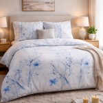Pościel satyna bawełniana 220x200 w pastelowe błękitne kwiatki, leżąca na łóżku. Widoczne poduszki z dopasowanym wzorem. Tło neutralne szare, proste, z dodatkami w postaci książek i dekoracji na półce. Tekstura satyny błyszcząca.