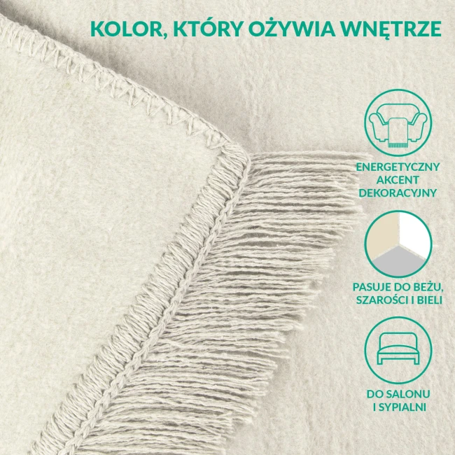 Koc bawełniany 150x200 cm w kremowym kolorze z frędzlami. Widoczna tekstura materiału, starannie wykończone brzegi. Idealny jako dekoracyjny akcent w salonie lub sypialni, pasuje do beżu, szarości i bieli.
