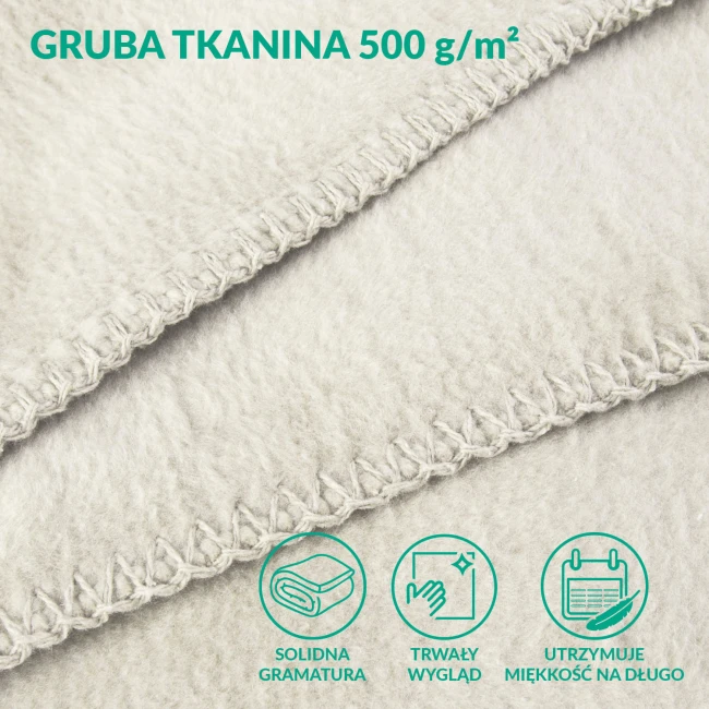 Kremowy koc bawełniany 150x200 cm z frędzlami, wykonany z grubej tkaniny 500 g/m². Zbliżenie na teksturę i wykończenie brzegów, które podkreślają solidność materiału. Idealny do użytku w domu lub na tarasie.