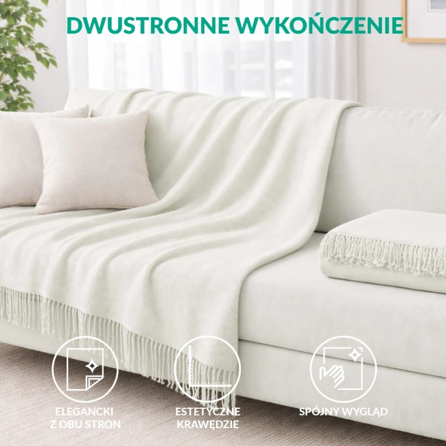 Kremowy koc bawełniany 150x200 cm z frędzlami, leżący na jasnej kanapie. Widoczne poduszki w kolorze beżowym. Koc ma dwustronne wykończenie i estetyczne krawędzie, co podkreśla jego elegancki wygląd w domowym wnętrzu.