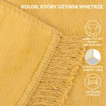 Koc bawełniany 150x200 cm w odcieniu żółtym, rozłożony na płasko. Widoczne frędzle na krótszym boku oraz delikatna faktura materiału. Kąt ujęcia zbliżony, ukazujący detale obszycia. Idealny do użytku domowego jako dekoracja lub do przykrycia.