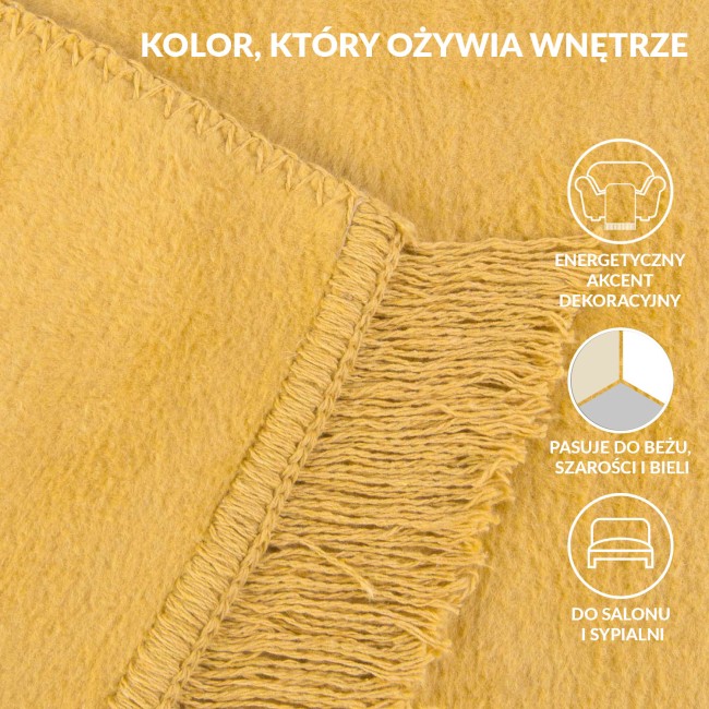 Koc bawełniany 150x200 cm w odcieniu żółtym, rozłożony na płasko. Widoczne frędzle na krótszym boku oraz delikatna faktura materiału. Kąt ujęcia zbliżony, ukazujący detale obszycia. Idealny do użytku domowego jako dekoracja lub do przykrycia.