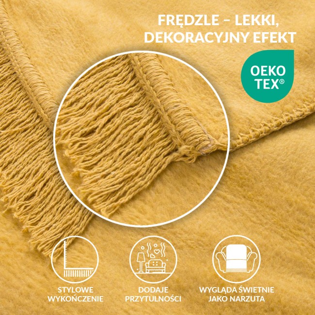 Koc bawełniany w kolorze żółtym 150x200 cm, z frędzlami, rozłożony na gładkiej powierzchni, z widoczną, teksturowaną tkaniną i starannym wykończeniem krawędzi. Frędzle dodają charakteru.