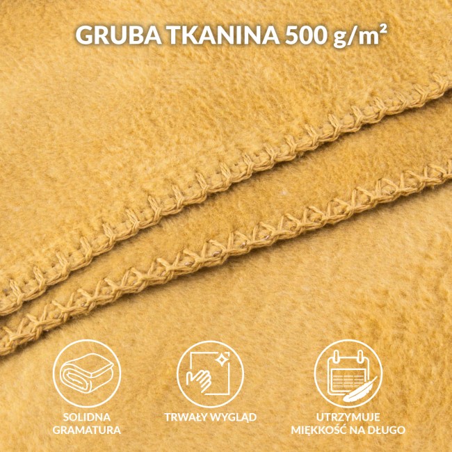 Koc bawełniany 150x200 w odcieniu żółtym, z frędzlami. Na fotografii widoczny z bliska, w złożonej pozycji, z wyraźnym przeszyciem wzdłuż krawędzi. Faktura materiału jest miękka i przyjemna w dotyku.