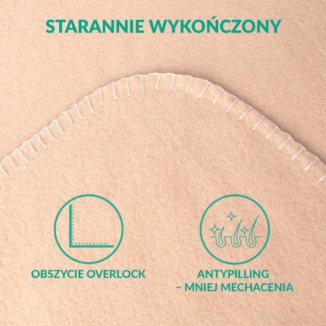 Koc polarowy 150x200 cm w kolorze beżowym, wykonany z miękkiego materiału z białym, widocznym przeszyciem na brzegach. Zbliżenie na detal faktury, koc leży na płaskiej powierzchni.