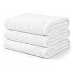 Biały ręcznik hotelowy AQUA o wymiarach 50x100 cm, wykonany z materiału o gramaturze 400 g/m². Złożony w trzech stosach, gładka faktura, widoczne wykończenie brzegów.