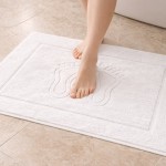 Dywanik łazienkowy Rosa w kolorze białym, o wymiarach 50x70 cm i gramaturze 500 g/m², z wyraźnym wzorem stóp. Ułożony na podłodze, z widoczną stopą, na gładkiej powierzchni. Tekstura miękka, idealna do użytku w łazience.