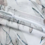 Pościel satyna bawełniana 180x200 Azura w kolorze białym z delikatnymi niebieskimi liśćmi, widoczny zamek błyskawiczny na poszewce. Materiał gładki, o subtelnej fakturze, idealny do sypialni.