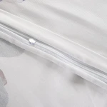 Pościel satynowa 220x200 w kolorze białym z dużymi pastelowymi niebieskimi kwiatami. Widoczny zamek błyskawiczny na poszwie. Gładka, błyszcząca faktura materiału. Idealna do eleganckiej sypialni.
