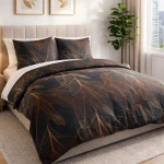 Pościel bawełniana 180x200 cm w ciemno szarym kolorze, ozdobiona miedzianymi liśćmi. Zestaw zawiera poszewki na poduszki i narzutę. Produkt leży na łóżku z jasnym zagłówkiem, w tle widoczna roślina oraz okno.