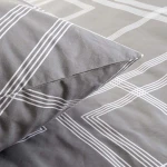 Pościel bawełniana 160x200 w odcieniu szarości z minimalistycznym wzorem geometrycznym w białe linie. Zbliżenie na poduszkę i część poszwy, ułożone na płasko. Materiał matowy, gładki, bez widocznych napisów czy logo.