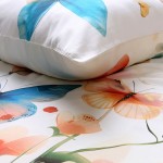 Pościel satyna bawełniana 220x200 z kolorowymi motylami i kwiatami. Widoczna poduszka z delikatnym nadrukiem na tle jasnego materiału. Kwiaty w odcieniach różu i pomarańczu, motyle w niebieskiej tonacji, tworzące harmonijną kompozycję.